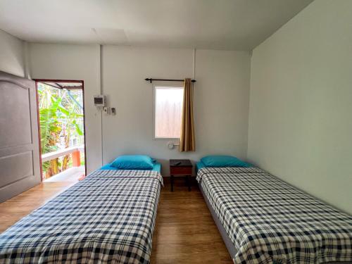 two beds in a room with a window at Baan Suan Tondin in Ban Du Son
