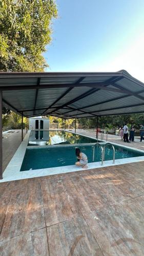 a woman sitting under a pavilion next to a swimming pool at Chandan resort in Chitrāwal