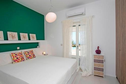 a bedroom with a white bed and a green wall at villa zakintos in Aspro Chorio Paros