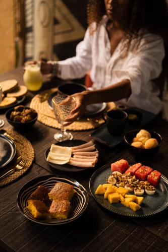 a woman sitting at a table with plates of food at Villa Bakari in Arraial d'Ajuda