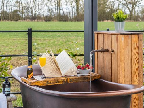 a bath tub filled with books and a glass of wine at Uk47693 - Piglet Cottage in Wimbish