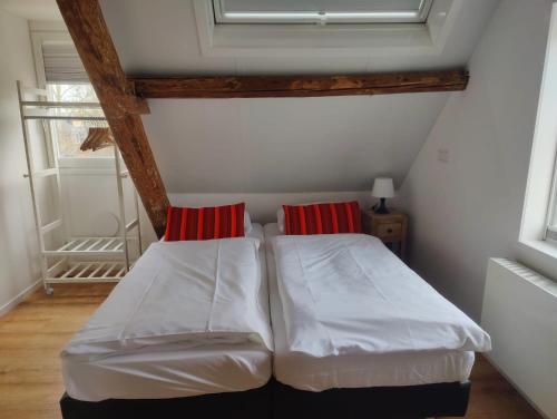 a bedroom with two beds with red pillows on them at Studio@Domburg in Domburg