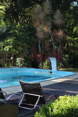 a swimming pool with two chairs and trees at Pousada Recanto Do Costão in Florianópolis