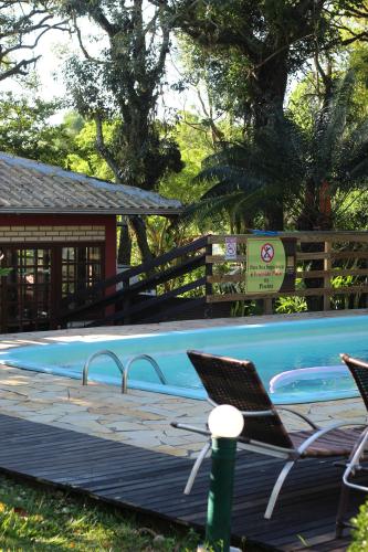 a swimming pool with two chairs sitting on a deck at Pousada Recanto Do Costão in Florianópolis