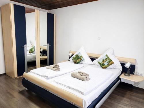 a bedroom with a bed with white sheets and a mirror at Ferienhaus Richard in Eschwege