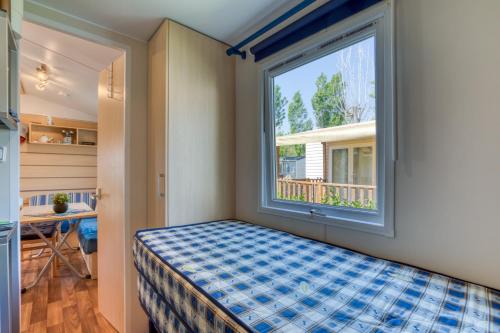 a small bedroom with a window and a bed at Location Mobilhome Agde in Agde