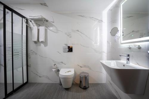 a white bathroom with a toilet and a sink at Buyuk Velic Hotel in Gaziantep
