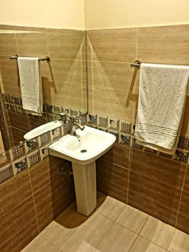 a bathroom with a sink and a mirror and towels at Shelton Hotel Johar Town Lahore in Lahore