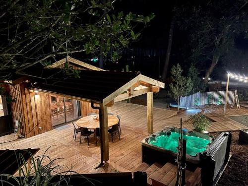 a deck with a table and a hot tub at Le Chalet Maguide in Biscarrosse