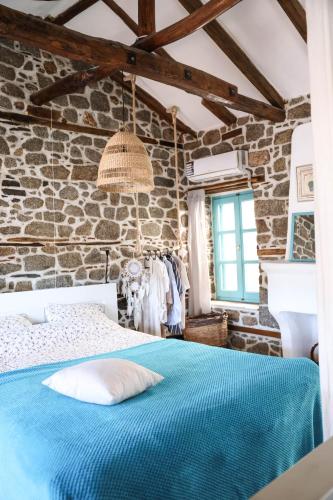 a bedroom with a blue bed and a stone wall at House Marika - between Sea & mountains in Sykia Chalkidikis