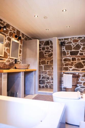 a bathroom with a toilet and a stone wall at House Marika - between Sea & mountains in Sykia Chalkidikis