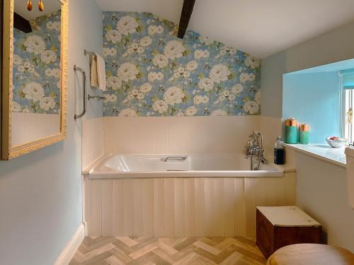 a bath tub in a bathroom with floral wallpaper at Rose Cottage in Richmond