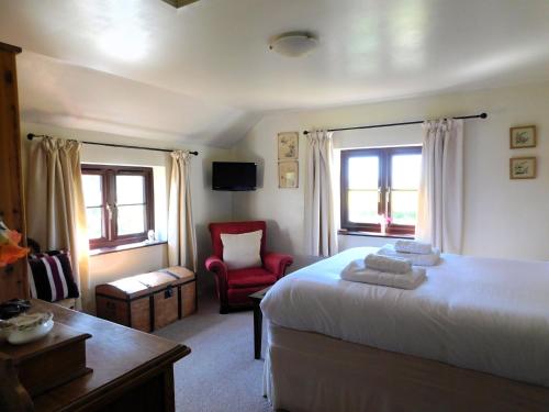 a bedroom with a bed and a red chair at Beechwood Cottage in Filby