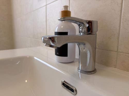a faucet with a bottle of soap on a sink at Malpensa Stay Express Self check-in in Gallarate