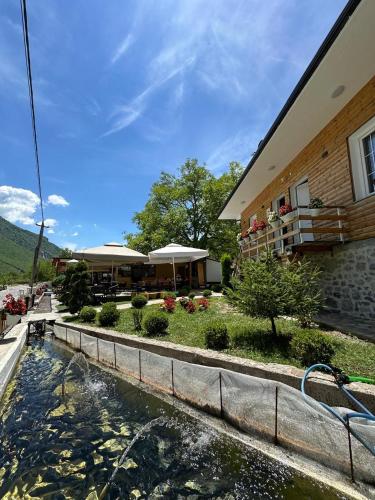 a house with a pond in front of a building at Samuel's Rooms in Theth