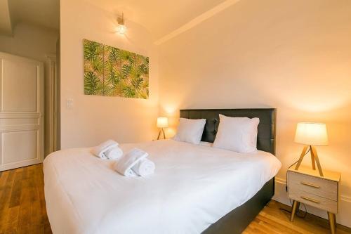 a bedroom with a large white bed with two pillows at Le Cote D'Or in Dijon