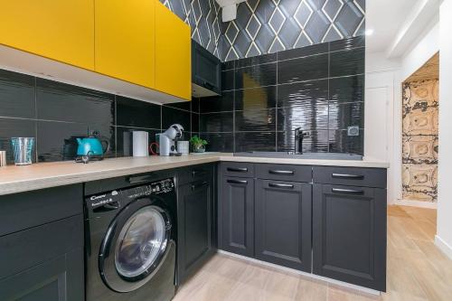 a kitchen with black cabinets and a washing machine at Le Cote D'Or in Dijon