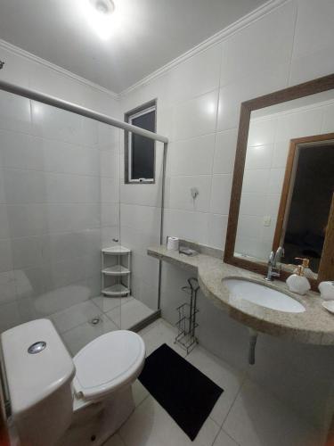 a white bathroom with a toilet and a sink at Apartamento em Guarapari in Guarapari