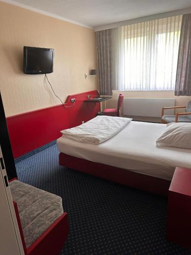 Ein Hotelzimmer mit zwei Betten und einem Fernseher an der Wand. in der Unterkunft Hotel Seegarten Quickborn in Quickborn