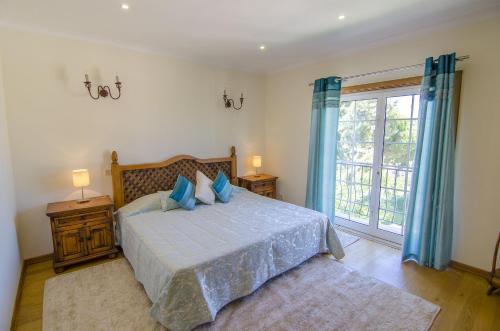 a bedroom with a bed with blue pillows and a window at Villa Lira by Algarve Holidays in Almancil