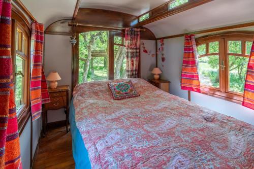 a bedroom in a train car with a bed and windows at La Roulotte Authentique in Grignan