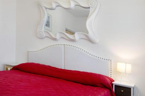 a bedroom with a red bed with a mirror on the wall at Erikbeach Bilo in Bibione