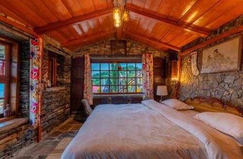 a bedroom with a large bed and a stone wall at The Boho Mukteshwar in Mukteshwar