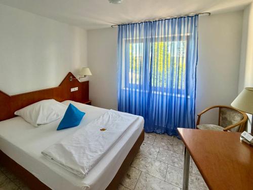 ein Schlafzimmer mit einem Bett und einem Fenster mit blauen Vorhängen in der Unterkunft Hotel am Buchwald in Esslingen