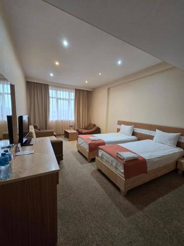 a hotel room with two beds and a television at Gabala Tufandag City Hotel in Gabala