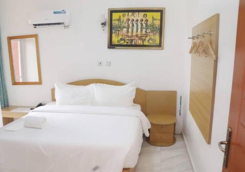 a bedroom with a large white bed and a box at Aotel Hotel Lagos Owodunni in Ikeja