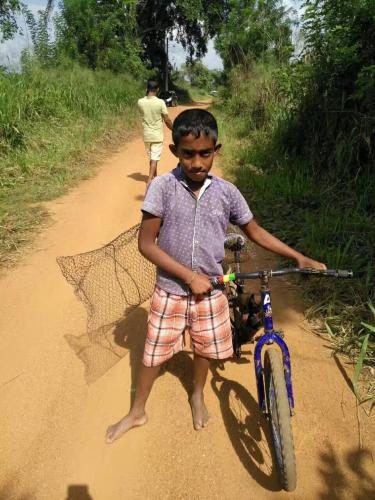 a young boy holding a bike on a dirt road at Nelu Villa Sigiriya in Sigiriya