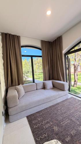 a couch in the middle of a room with windows at Raduga Resort Orion in Chon-Sary-Oy