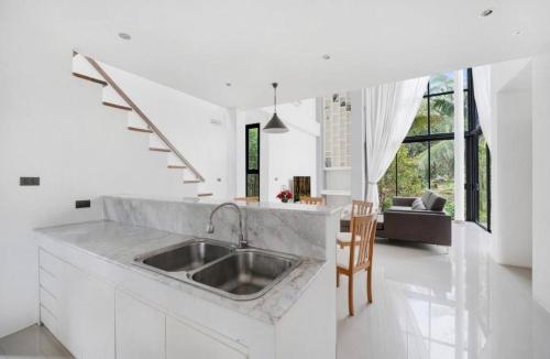 a white kitchen with a sink and a living room at Anas house in Lipa Noi in Lipa Noi
