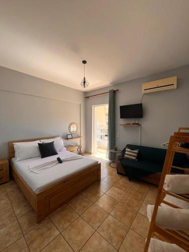 a bedroom with a bed and a tv and a couch at Milto's Rooms in Himare