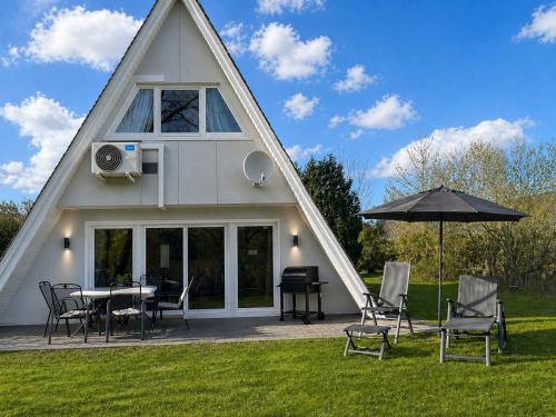 a triangular house with a table and chairs and an umbrella at Dachzelt Oase Damp in Damp