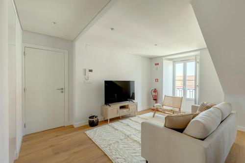 a white living room with a couch and a television at Tulum Bohemian 2BR Apartment in Caparica