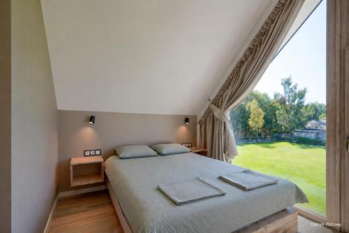 a bedroom with a bed and a large window at Jesionowa 3 Domki in Rowy