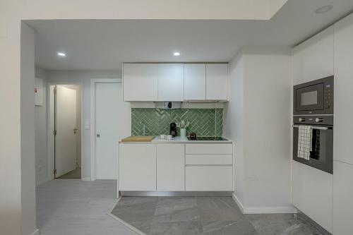 a kitchen with white cabinets and a microwave at Seixal River Retreat in Amora