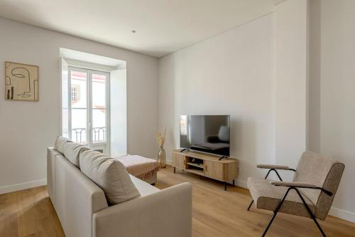a living room with a couch and a television at Vienna 1BR Calm & Cozy Escape in Caparica