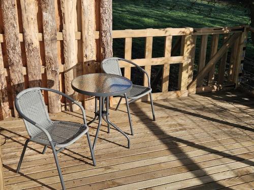 two chairs and a table on a wooden deck at Cosy Treehouse in Pontypool