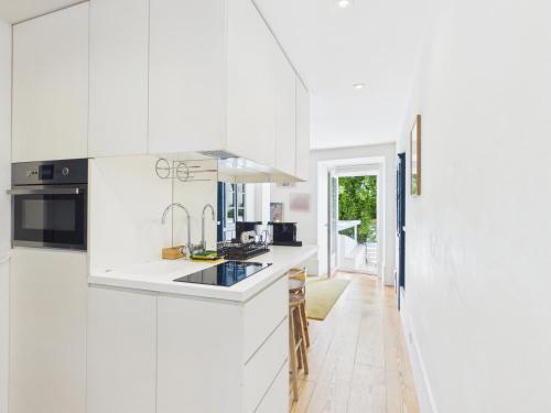 a white kitchen with a sink and a stove at Cozy 1BR, Private Terrace & Pool – Estrela | By Airnest in Lisbon
