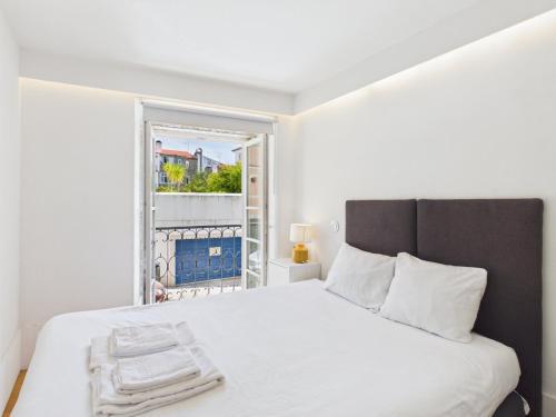 a bedroom with a white bed and a window at Cozy 1BR, Private Terrace & Pool – Estrela | By Airnest in Lisbon