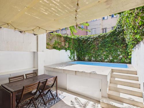 a patio with a table and a green wall at Cozy 1BR, Private Terrace & Pool – Estrela | By Airnest in Lisbon