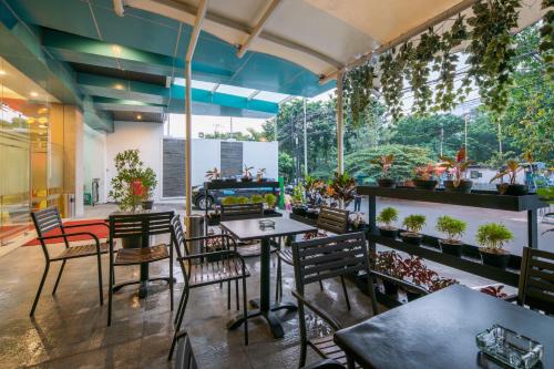 a restaurant with tables and chairs and potted plants at Hotel 88 Grogol Jakarta By WH in Jakarta