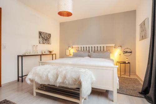 a white bedroom with a white bed with a white blanket on it at Halali Braunlage in Braunlage