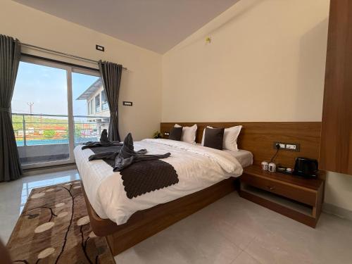 a bedroom with a large bed with a large window at Shreya Bungalow Mahabaleshwar in Mahabaleshwar