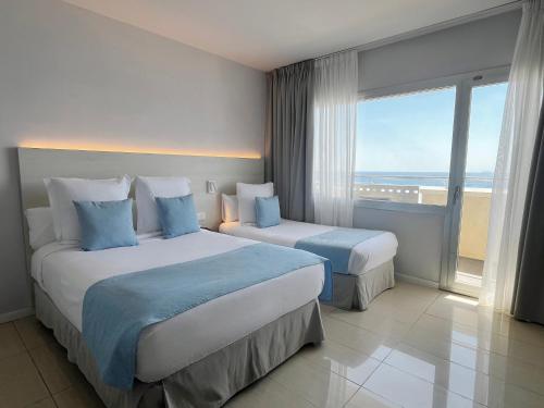 two beds in a hotel room with a view of the ocean at Hotel Excelsior in Lloret de Mar