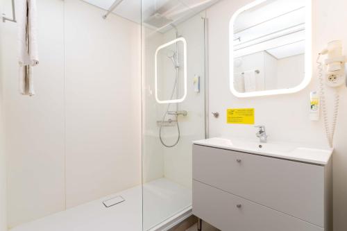 a white bathroom with a shower and a sink at SLEEEP Hotel Vösendorf in Vösendorf