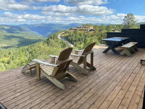 a wooden deck with two chairs and a picnic table at Authentic Cabin Life With Løefjell View in Rysstad