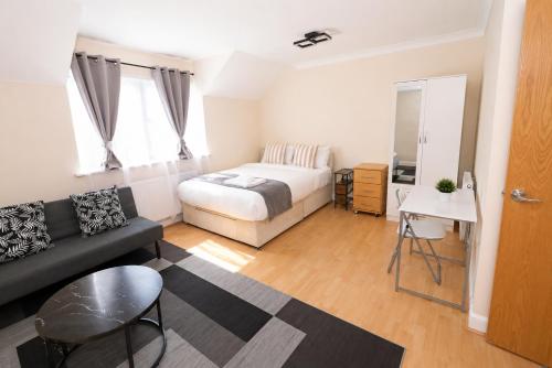 a bedroom with a bed and a couch and a table at Greenhithe Guest House in Stonewood